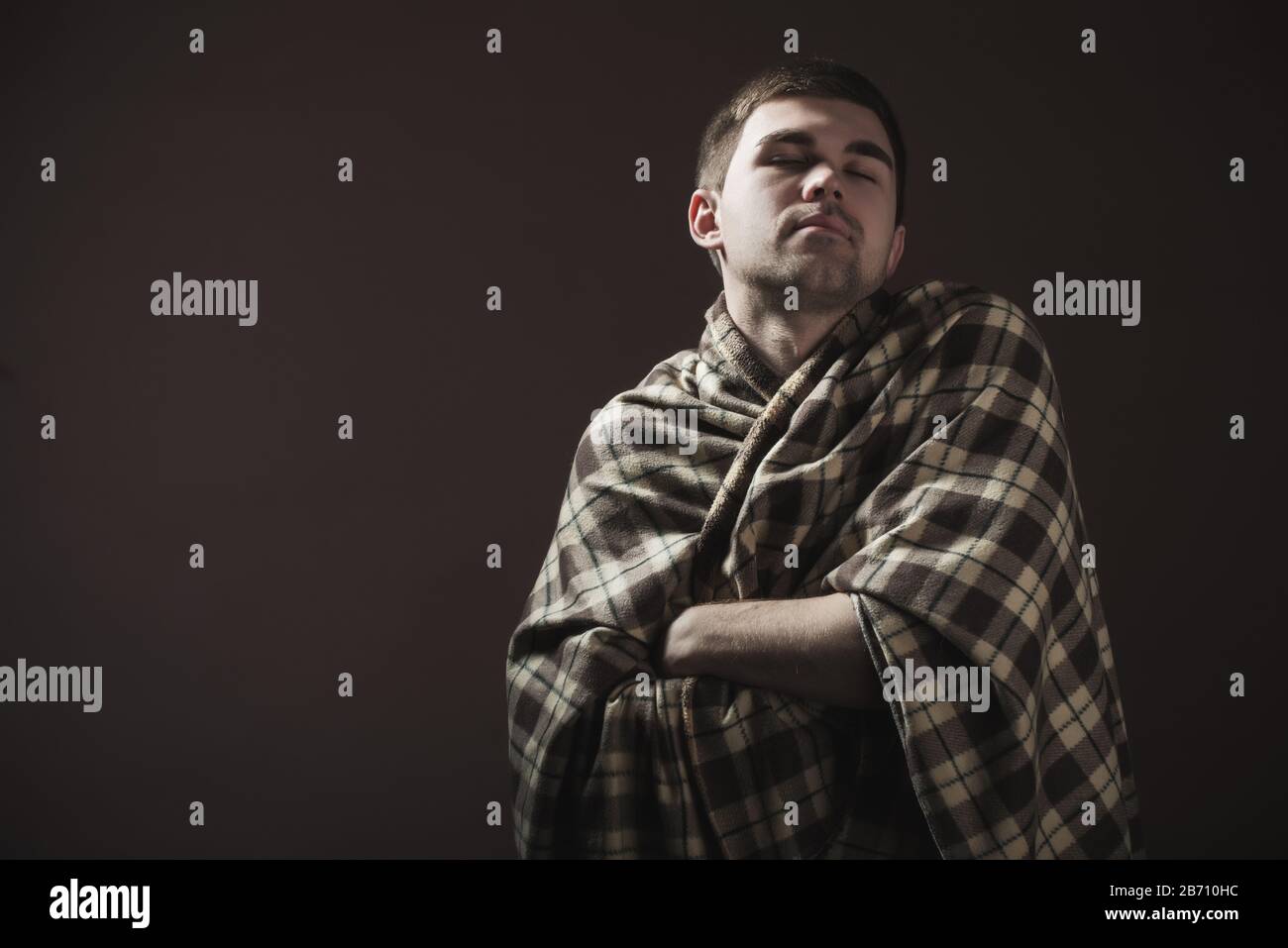 Porträt eines jungen, schläfrigen Mannes, der in eine Pflauge gewickelt ist. Konzept eines harten morgendlichen Erwachens und Arbeitsstimmung Stockfoto