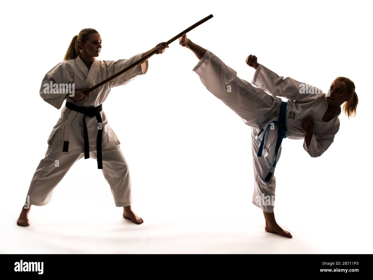 Training von zwei Mädchen in weißen Kimonos mit Sportgeräten und Karate-Ständer. Isoliert auf weißem Hintergrund Stockfoto