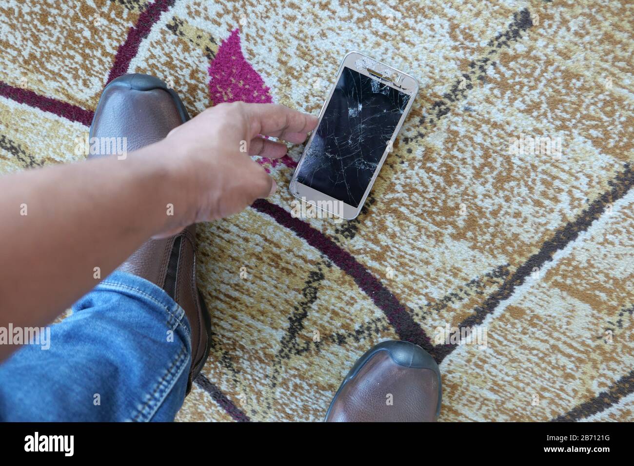 Mann Handpflücken zerbrochenes Smartphone vom Boden Stockfoto