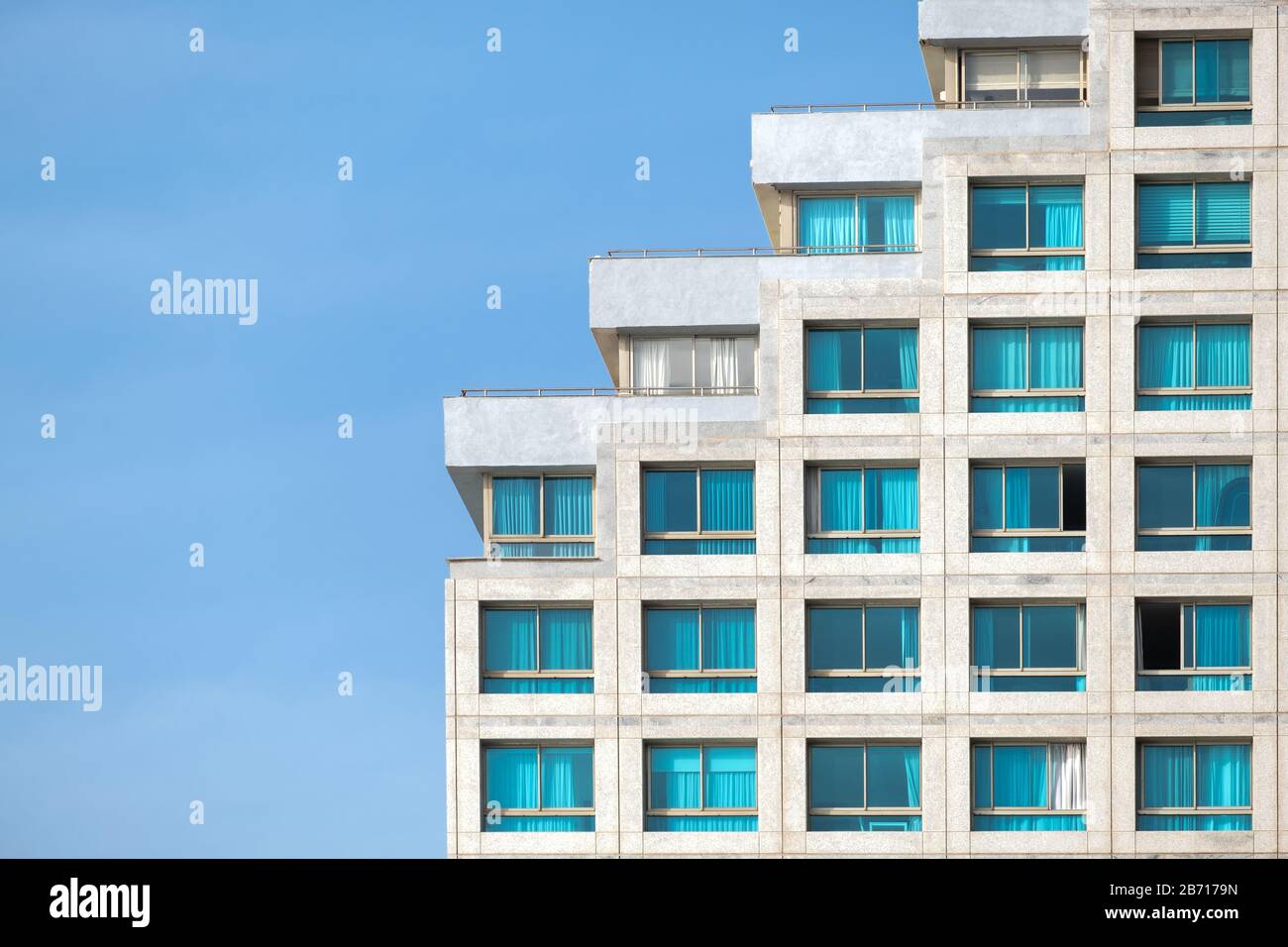Ein Fragment eines modernen Gebäudes gegen den blauen Tageshimmel, das nach dem Prinzip der Treppe gebaut ist. Stockfoto
