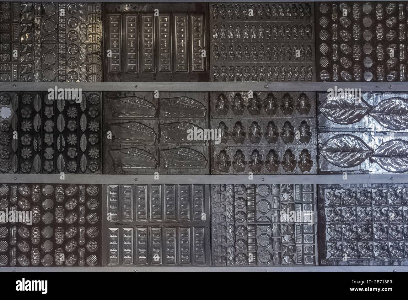 Formen zur Herstellung von Schokoladenbonbons und Bonbons in unterschiedlicher Form, die als Hintergrund angeordnet sind Stockfoto