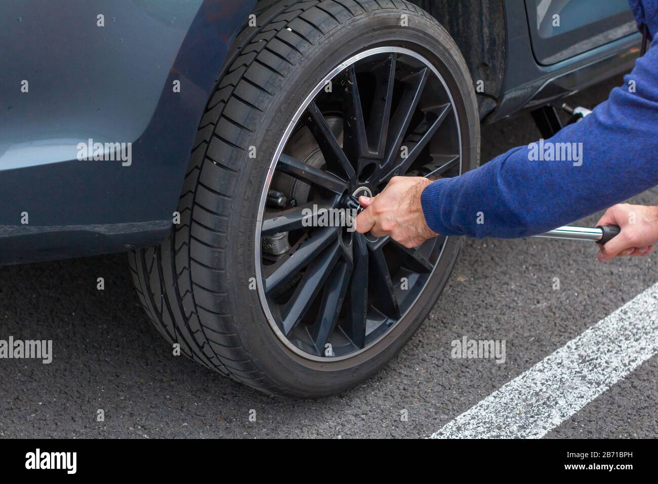 Nahaufnahme: Die Hände wechseln mit einem Schraubendreher ein Rad. Austausch von Winter- und Sommerreifen. Saisonales Reifenaustauschkonzept. Serviceprozess. Prag Stockfoto