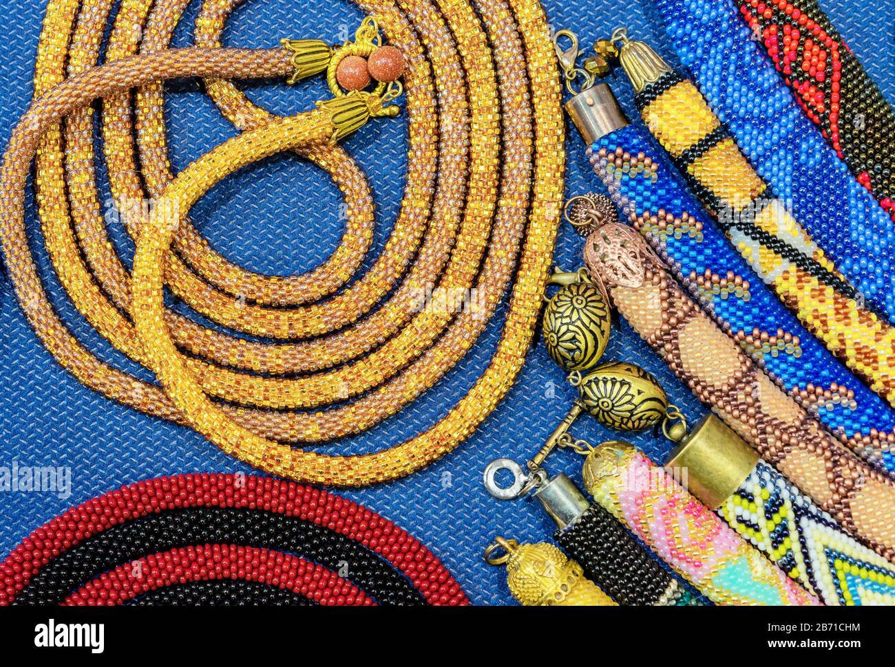 Ethnische Perlen mit verschiedenen Verzierungen werden mit der Technik des Webens mit Perlen hergestellt. Stockfoto