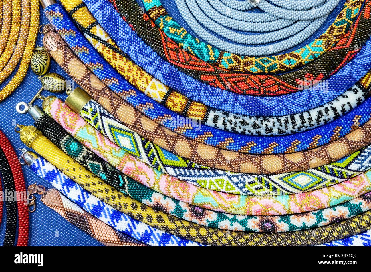 Ethnische Perlen mit verschiedenen Verzierungen werden mit der Technik des Webens mit Perlen hergestellt. Stockfoto
