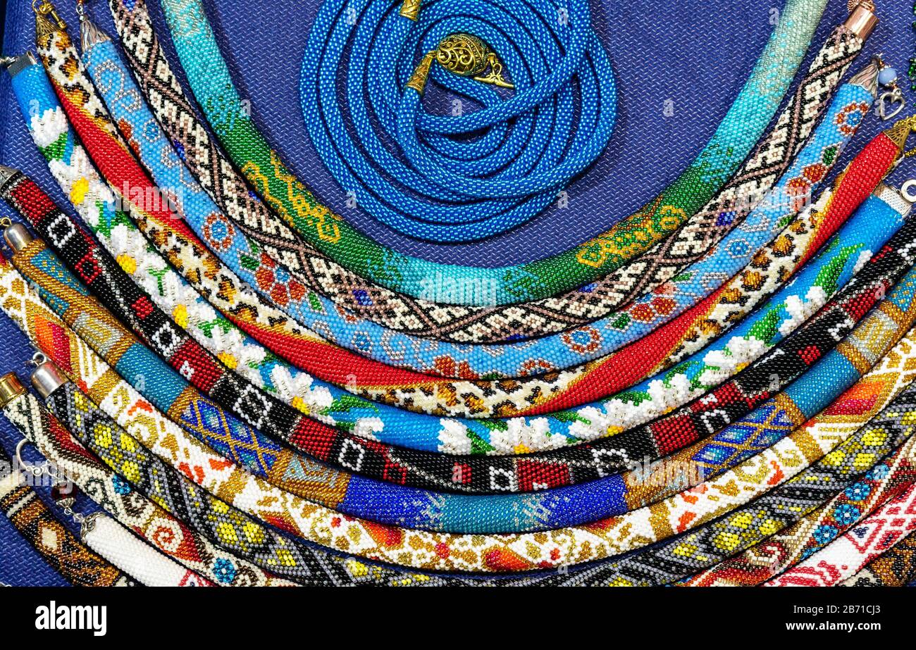 Ethnische Perlen mit verschiedenen Verzierungen werden mit der Technik des Webens mit Perlen hergestellt. Stockfoto