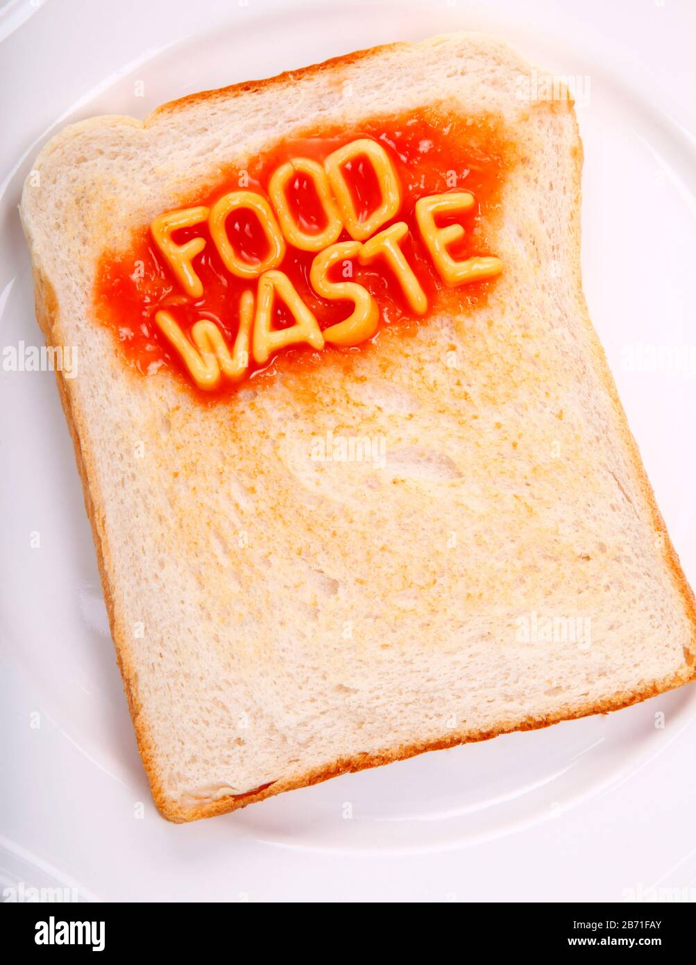 Die Wörter Lebensmittelverschwendung haben mit Spaghetti aus dem Alphabet auf einem Toaststück geschrieben Stockfoto