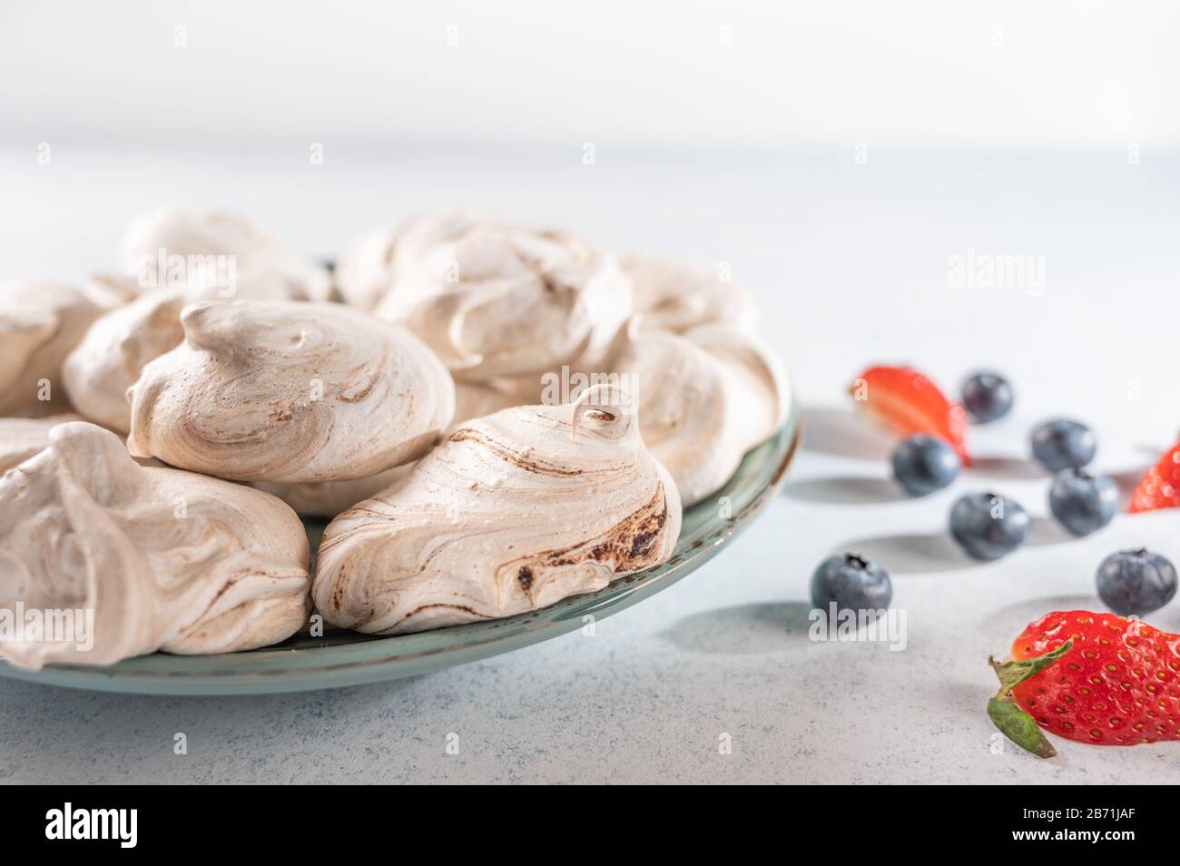 Hausgemachtes Dessert auf einem Teller mit leichtem Hintergrund. Serviette, Erdbeere und Blaubeeren. Kopierbereich Stockfoto