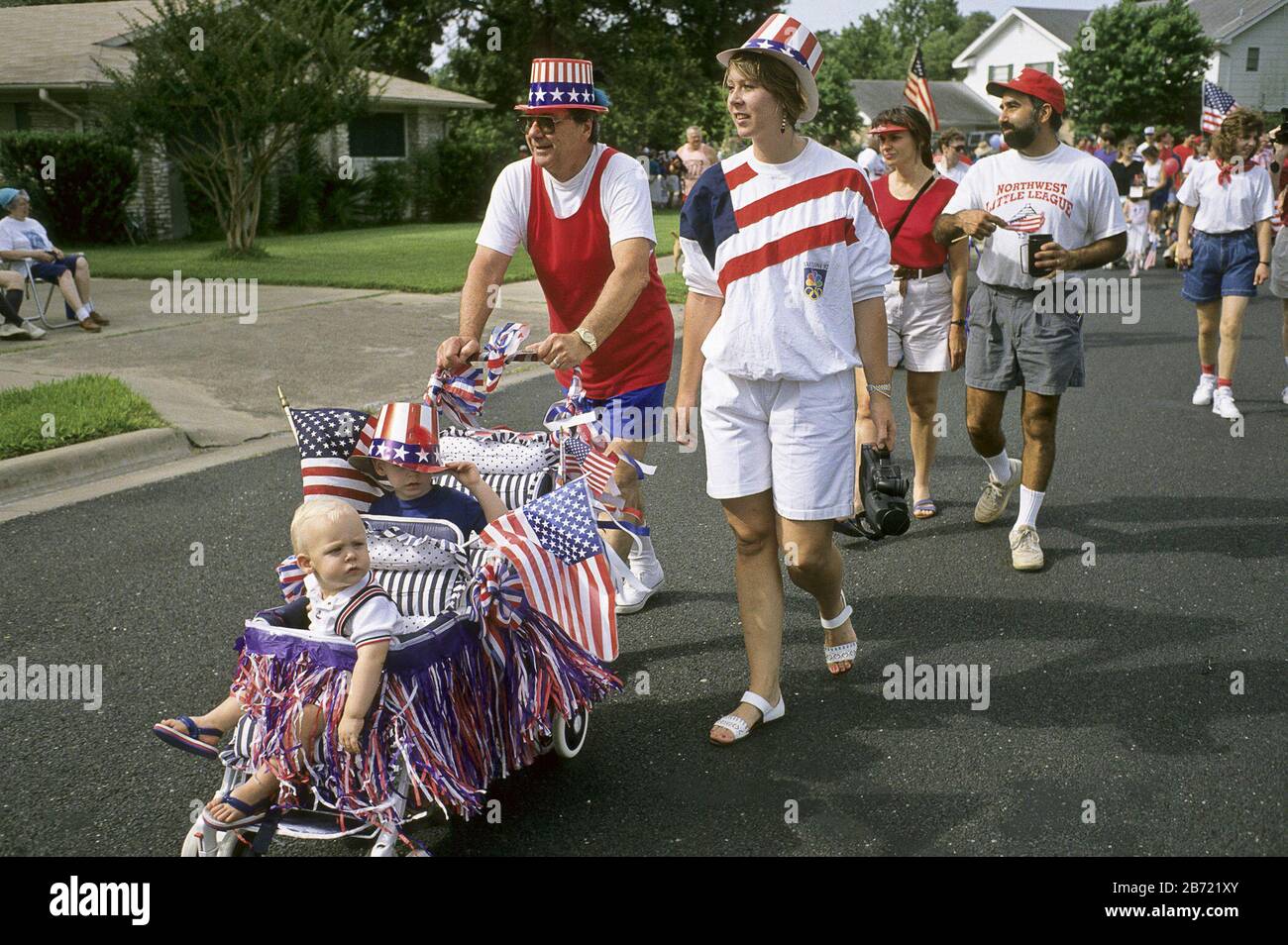 Austin, Texas, USA: Vater schiebt einen flaggendrapierten Kinderwagen, während die Familie in der Nachbarschaft spazieren geht, die Parade am 4. Juli. ©Bob Daemmrich Stockfoto