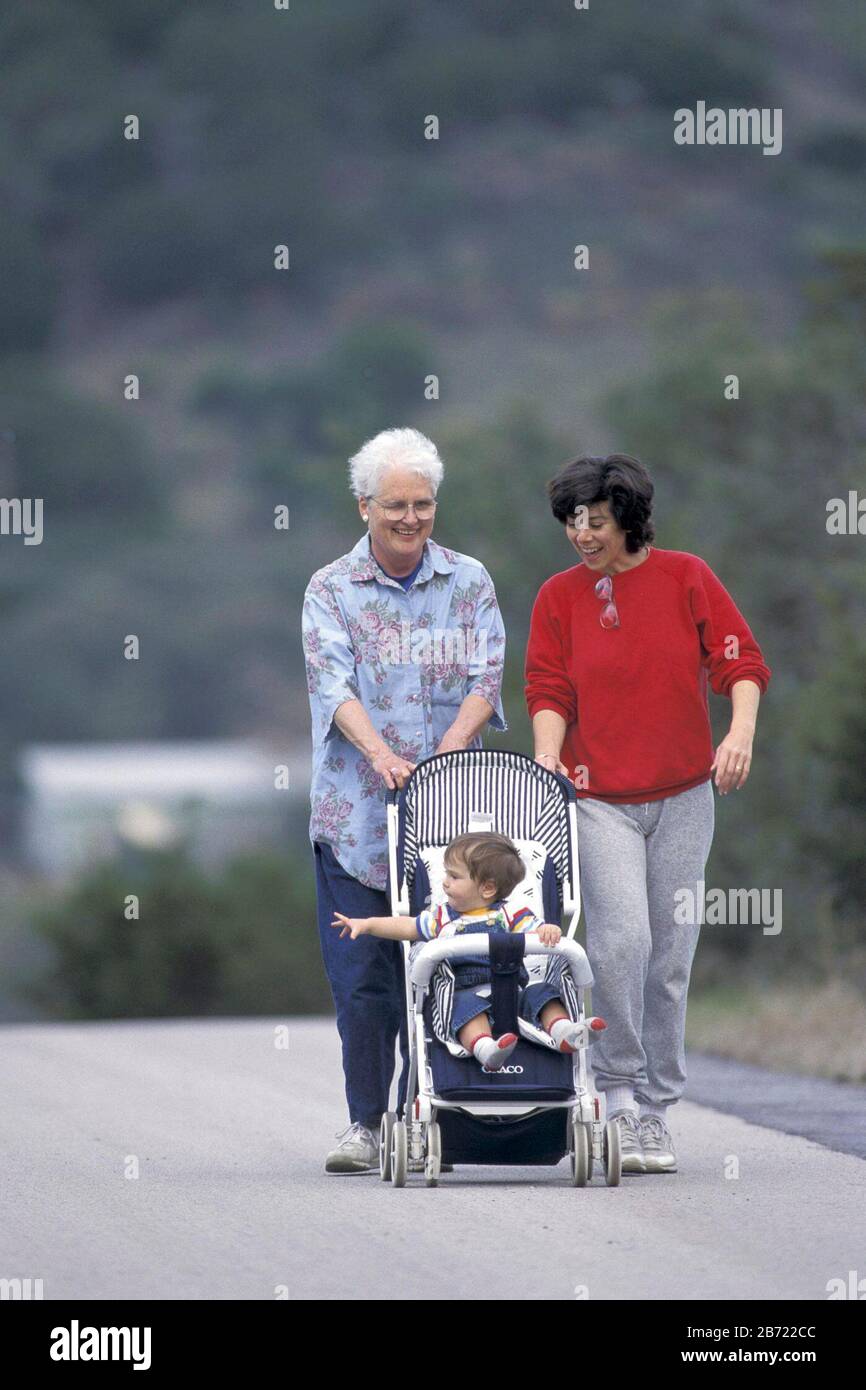 Mutter und Schwiegermutter schieben den zehn Monate alten Jungen in den Kinderwagen. HERR ©Bob Daemmrich / Stockfoto