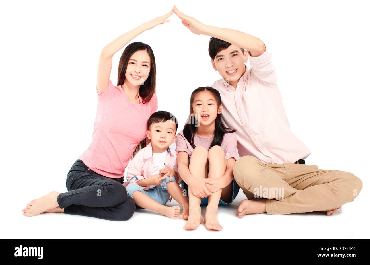 Fröhliche junge asiatische Familie sitzt auf dem Boden mit Heimatkonzept Stockfoto