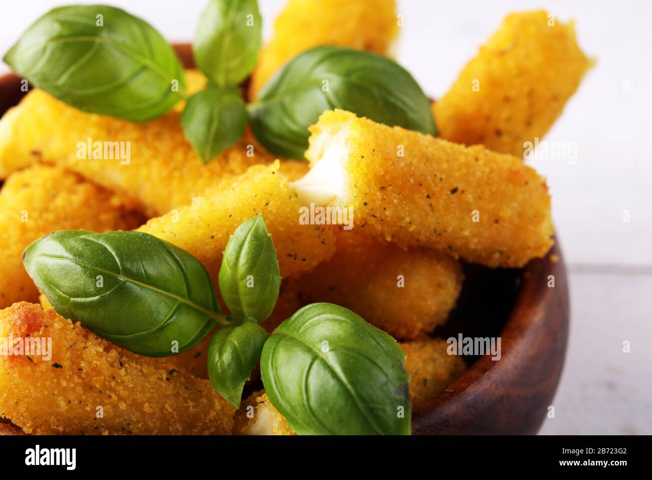Panierte Mozzarella-Käsestäbchen mit Basilikum auf dem Tisch Stockfoto