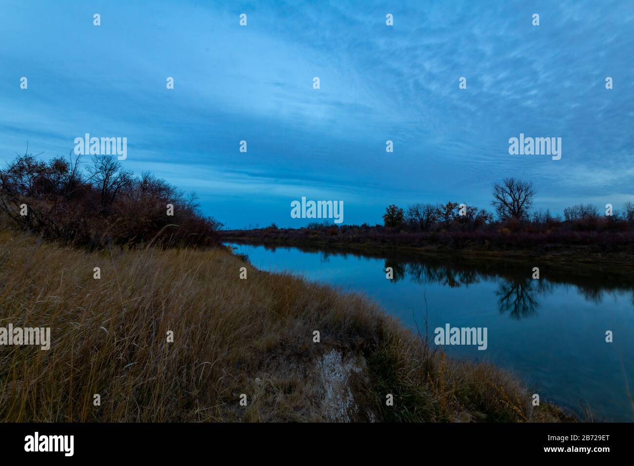 Sonnenuntergang spiegelt sich im ruhigen Wasser des South Saskatchewan River Stockfoto