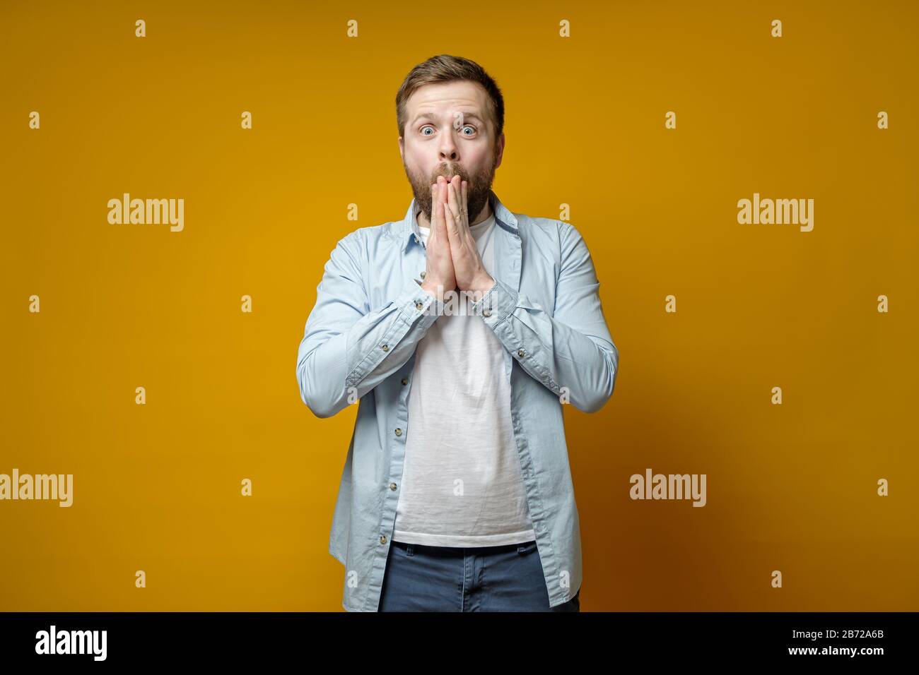 Der Mensch ist angenehm überrascht von einer unerwarteten Überraschung, er ist glücklich und in einem Stupor, hält die Hände am Mund und schaut auf die Kamera. Stockfoto