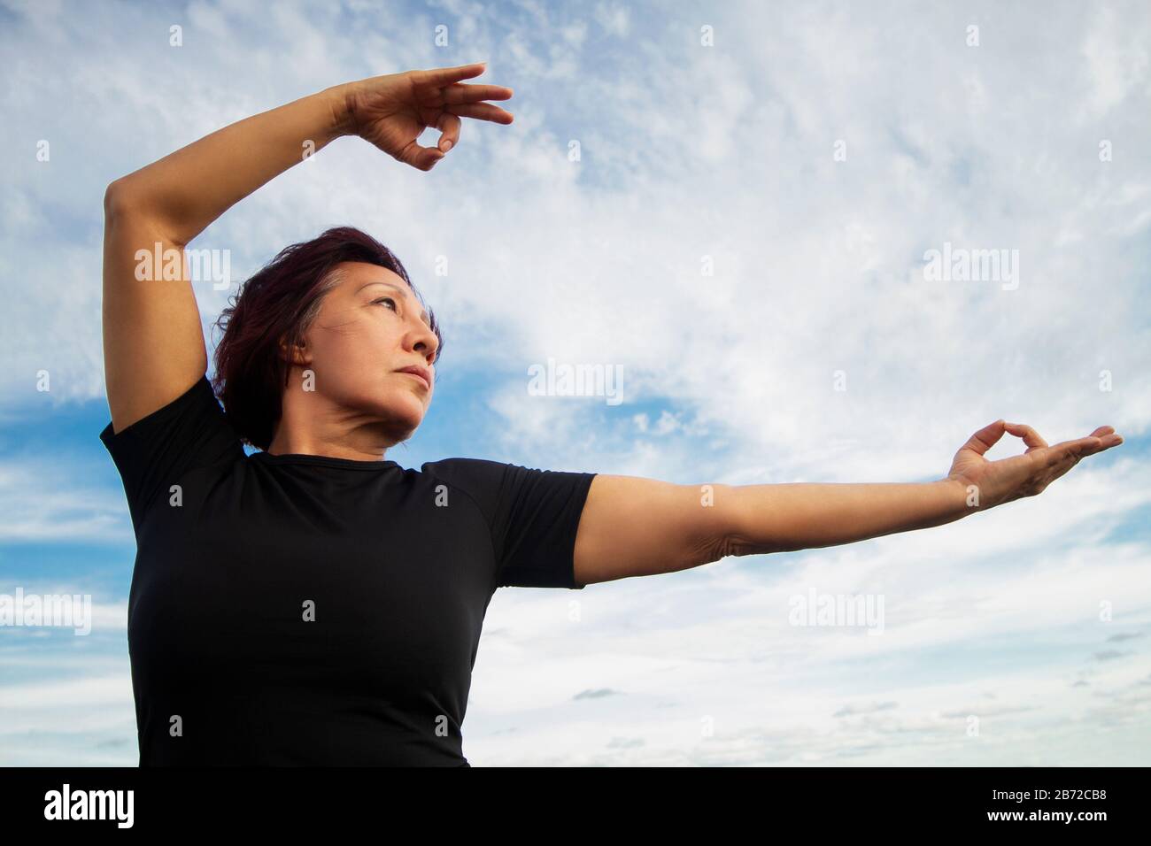 Aktive ältere Frau, die Tai Chi am Strand praktiziert. Stockfoto