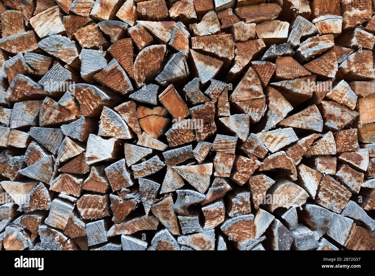 Isolierte Nahaufnahme von gestapeltem Brandholz/geschnittenes Holz - gehockt gegen eine Wand. Die meisten Protokolle haben eine Dreiecksform. Symbol für Wärme, Wärme, Winterzeit. Stockfoto