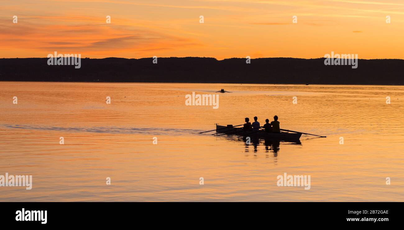 Die Gewinner: Silhouette mit Reihe/Ruderboot bei Sonnenuntergang. Vierköpfige Mannschaft. Konzept zur Zielerreichung nach harter Arbeit, Ausdauer, Koordination Stockfoto