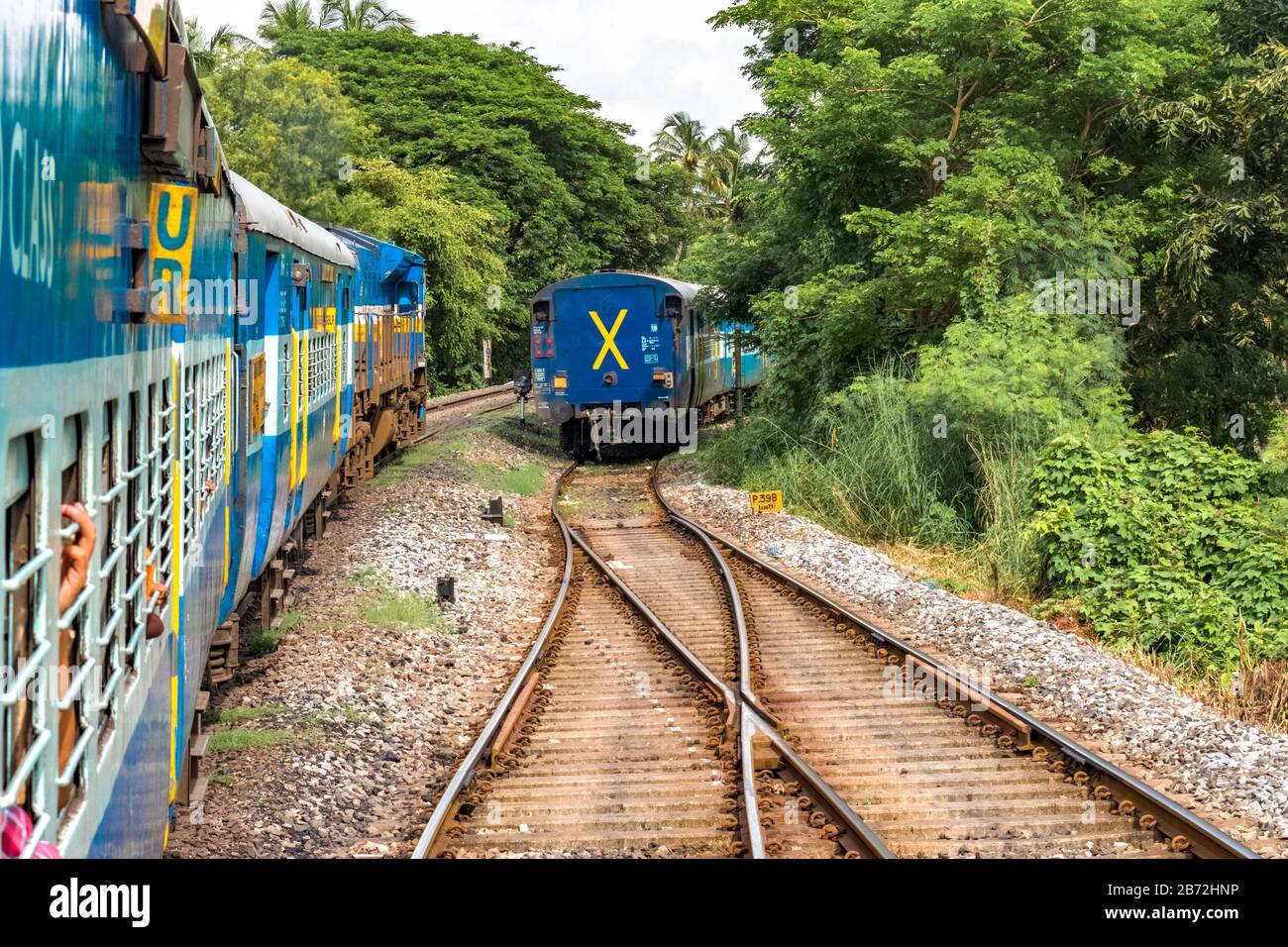 Der langsam fahrende Zug der Indian Railways, der von der Kreuzung abfährt und einen angehaltenen Zug mitten im Grün der Western Ghats überholen kann.Reisekonzept, Reise. Stockfoto