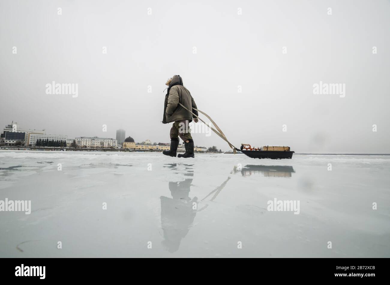 Der Mensch überquert den Fluss. Überschwemmte Straße auf Eis Stockfoto