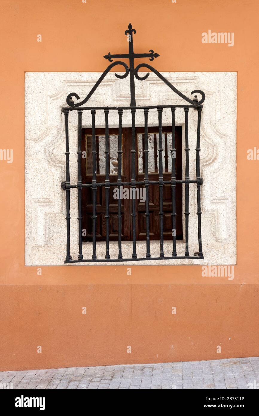 Antike Holz-Fenster mit schmiedeeisernen Gitter und geschnitzten Stein Rahmen an orange Wand. Stockfoto