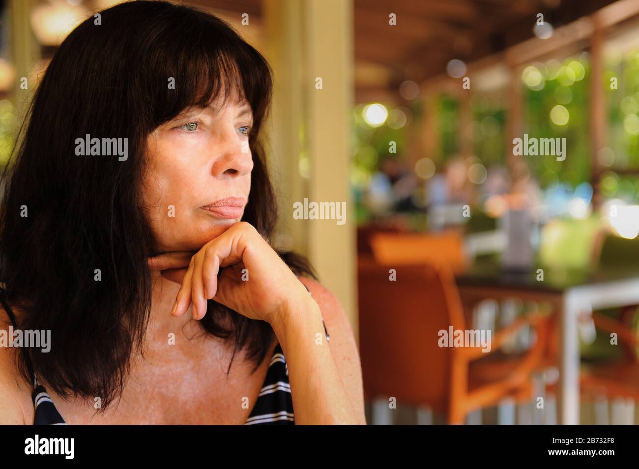Nahaufnahme der weiblichen Touristenhand, unter ihrem Kinn, mit Blick in die Ferne in einem Restaurant auf Fitzroy Island, Queensland. Stockfoto