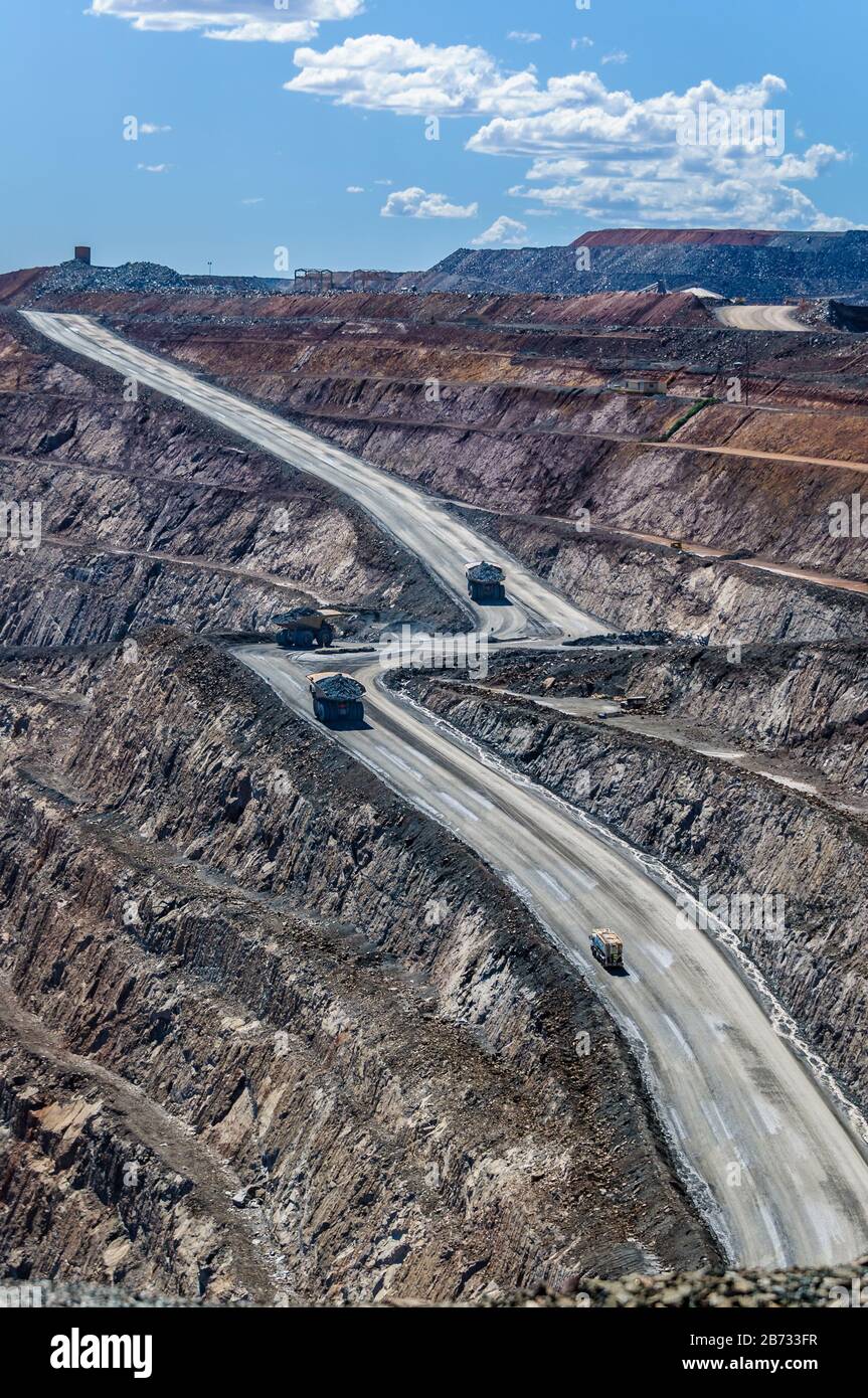 Vier riesige Minenwagen fahren auf einer steilen Straße auf einer großen, offenen Goldmine in Kalgoorlie, Western Australia. Stockfoto