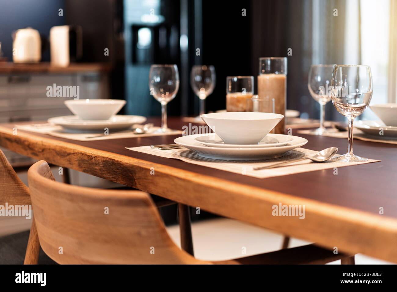 Eleganter Esstisch auf einem Holztisch mit Geschirr, Besteck, Utensil, Weingläsern und Kerzen. Tischset für gehobene Küche, luxuriöse Mahlzeit. Stockfoto