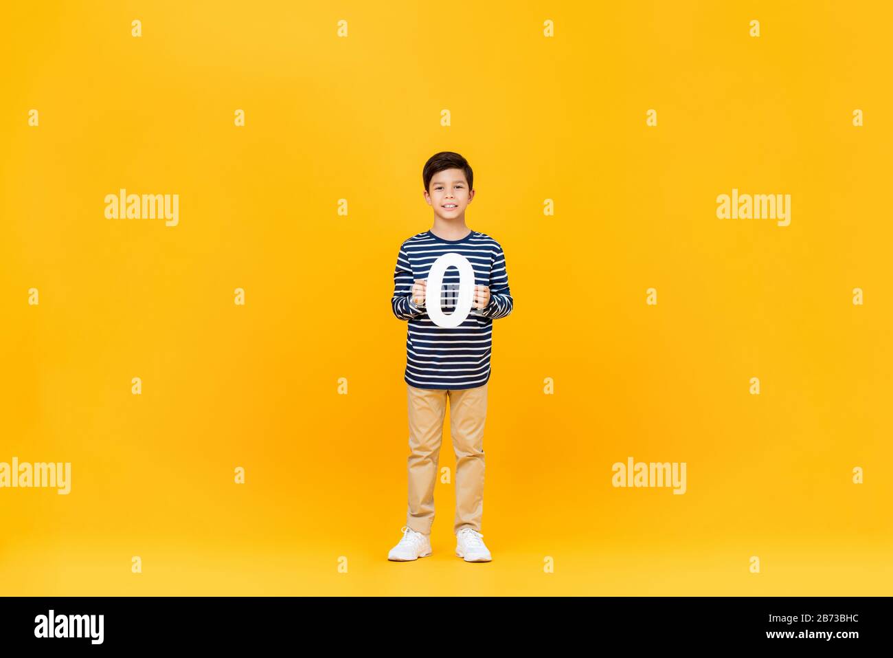 10 Jahre alter süßer kleiner Junge mit der Nummer Null auf gelbem Hintergrund Stockfoto