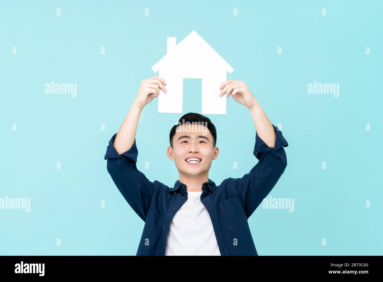 Fröhlicher junger Asiat, der das Schild oben auf hellblauem Hintergrund für Immobilienkonzepte isoliert hält Stockfoto Fröhlicher junger Asiat, der das Schild oben auf hellblauem Hintergrund für Immobilienkonzepte isoliert hält Stockfoto