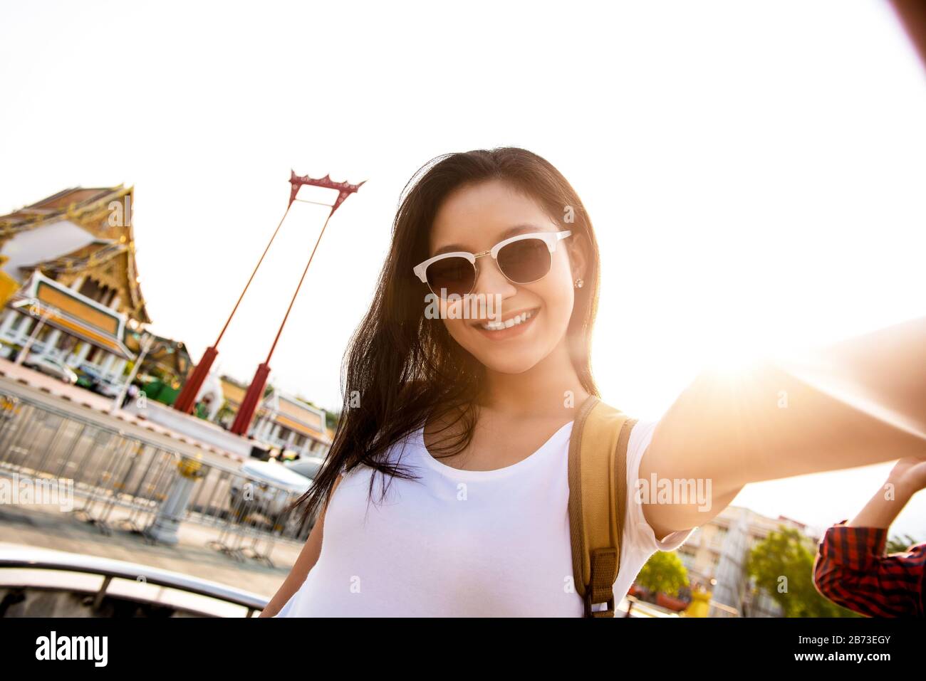 Lächelnde junge, schöne asiatische Frau, die eine Sonnenbrille trägt und auf ihrer Reise nach Bangkok Thailand einen selfie beim Giant Swing mitnimmt Stockfoto