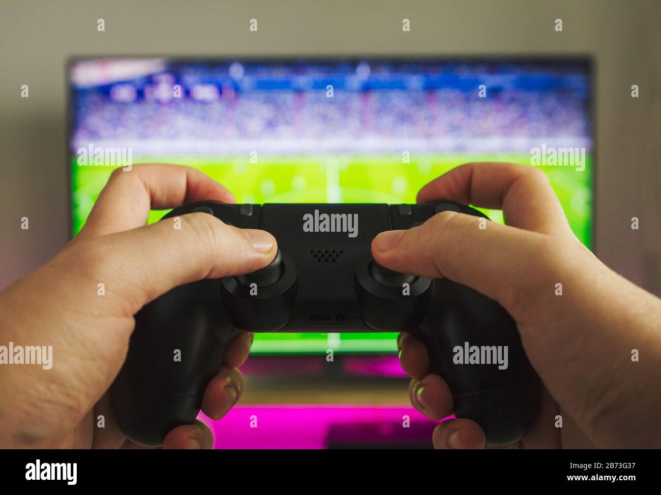 Fotos von einigen Händen mit einem Gamepad, das ein Fußballspiel auf der Spielkonsole spielt Stockfoto