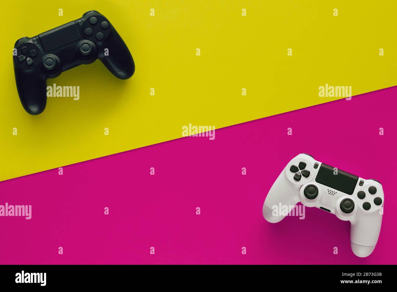 Stock-Foto von zwei Gamepads auf zwei farbigen Hintergründen und Kopierbereich in der Mitte Stockfoto