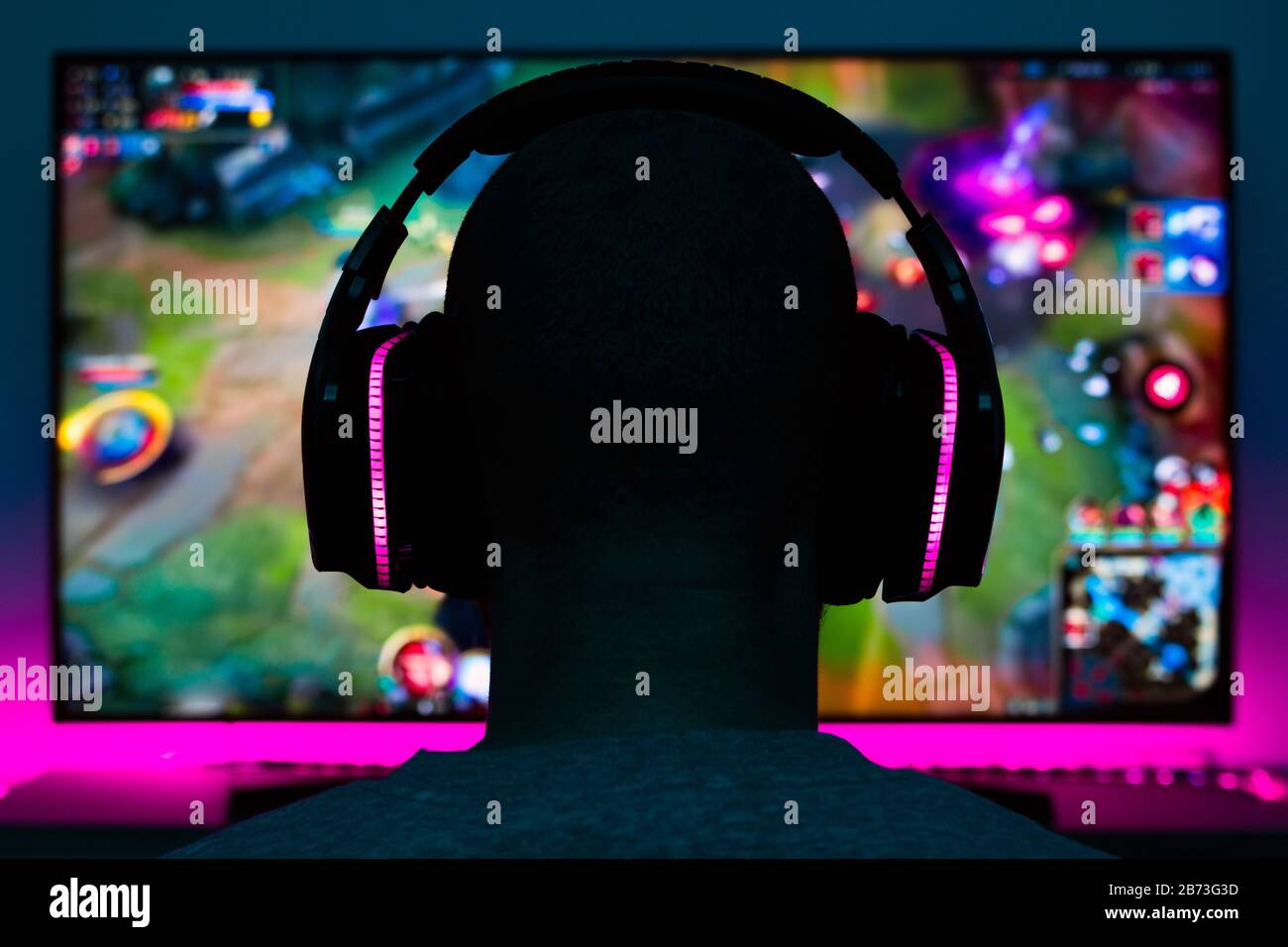 Stock-Foto eines Spielers mit Kopfhörern, der ein Videospiel vor dem fernseher spielt Stockfoto