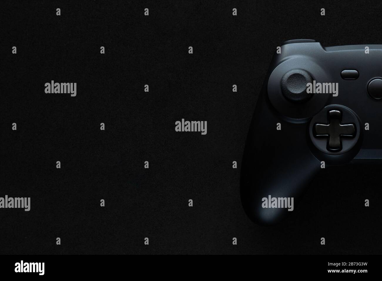 Stock-Foto eines schwarzen Gamepads auf einem texturierten schwarzen Hintergrund und Kopierbereich auf der linken Seite Stockfoto