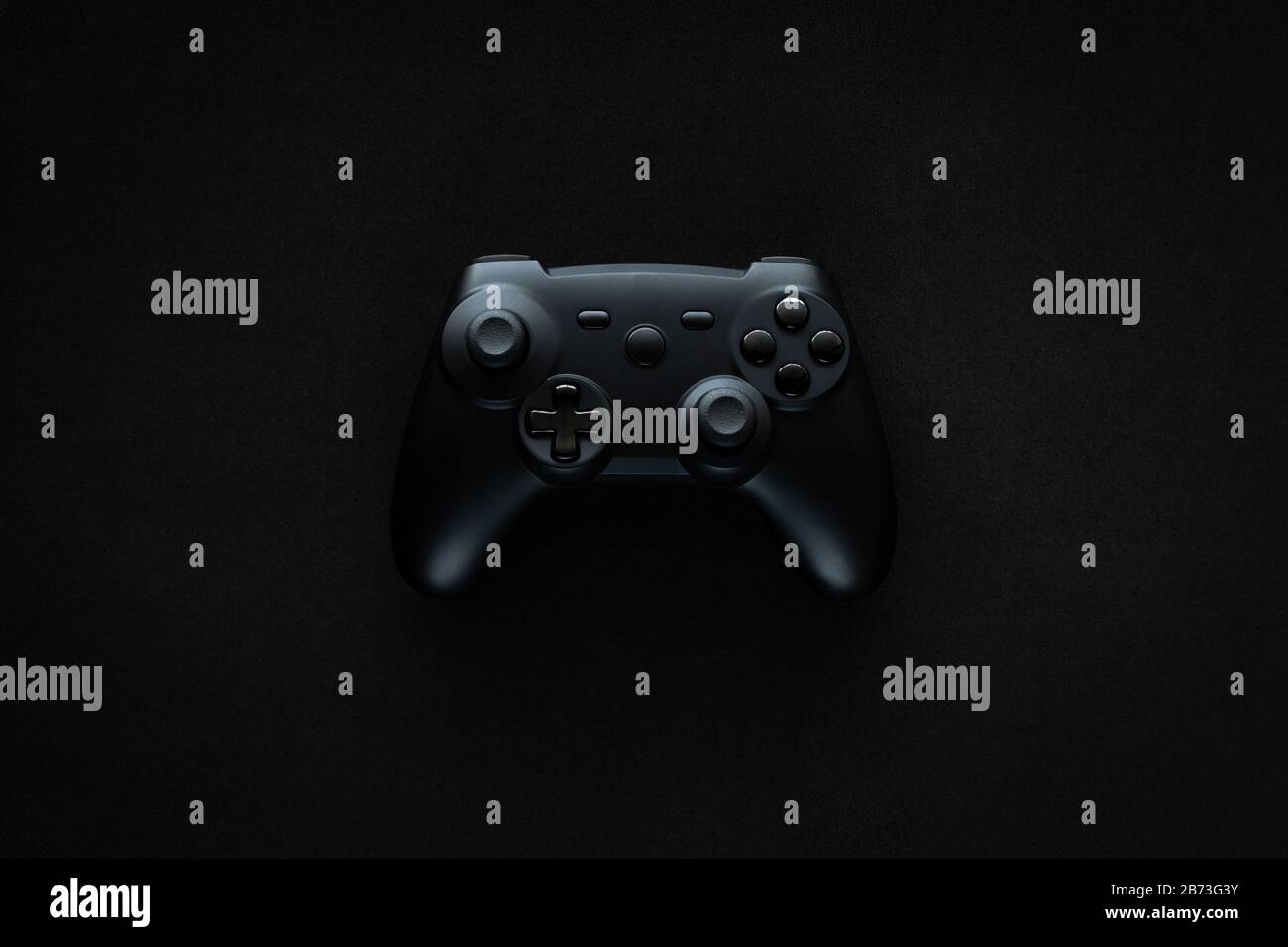 Stock-Foto eines schwarzen Gamepads inmitten eines schwarzen, strukturierten Hintergrunds Stockfoto