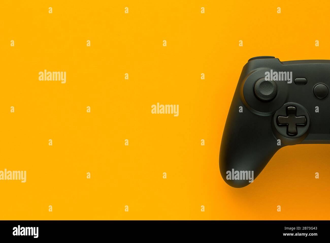 Stock-Foto eines schwarzen Gamepads auf gelbem Hintergrund und Kopierbereich auf der linken Seite Stockfoto