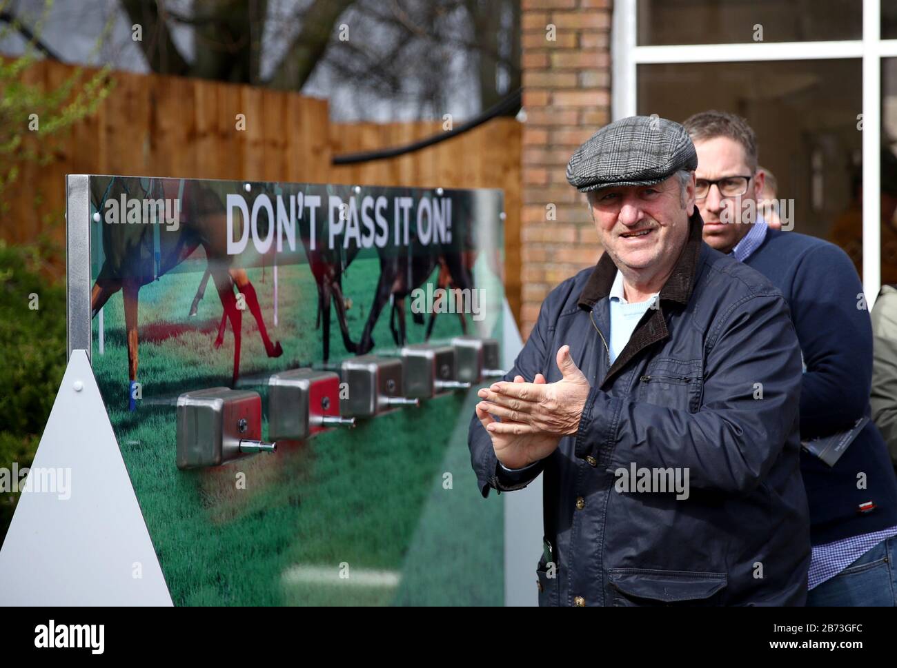 Racegoers verwenden Händedesinfektionsautomaten aufgrund des Coronavirus-Ausbruchs am vierten Tag des Cheltenham Festivals auf der Cheltenham Racecourse. Stockfoto