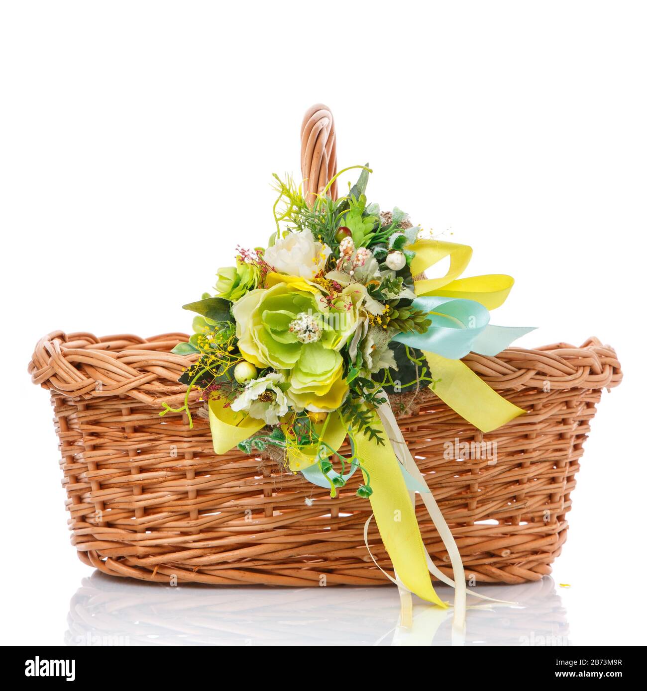 Korbbrauner Korb mit zarten pastellgrünen Blumen und Bändern auf weißem Hintergrund dekoriert Stockfoto