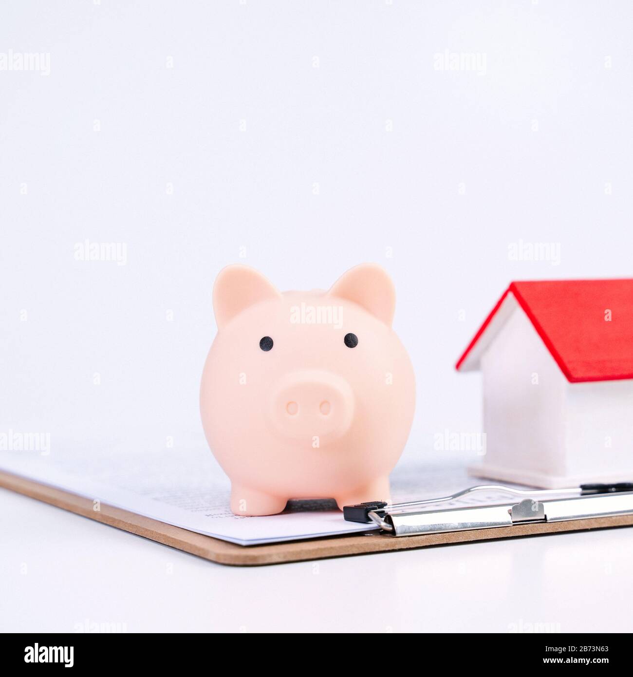 Finanzklage - Piggy Bank, wunderschönes rot-weißes Holzhausmodell auf weißem Hintergrund, spart Geld beim Kauf von Versicherungen, Nahaufnahme, Kopierplatz. Stockfoto