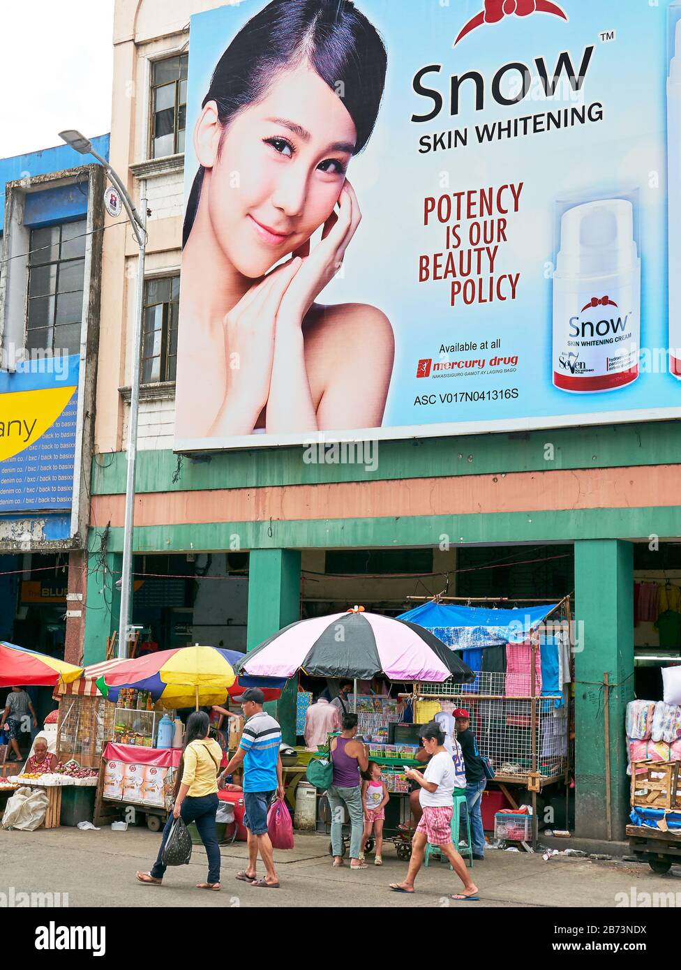 Divisoria Market, Manila, Philippinen: Plakat, auf dem junge asiaten für Produkte zur Hautaufhellung werben, Filipinos vorbeiziehen Stockfoto