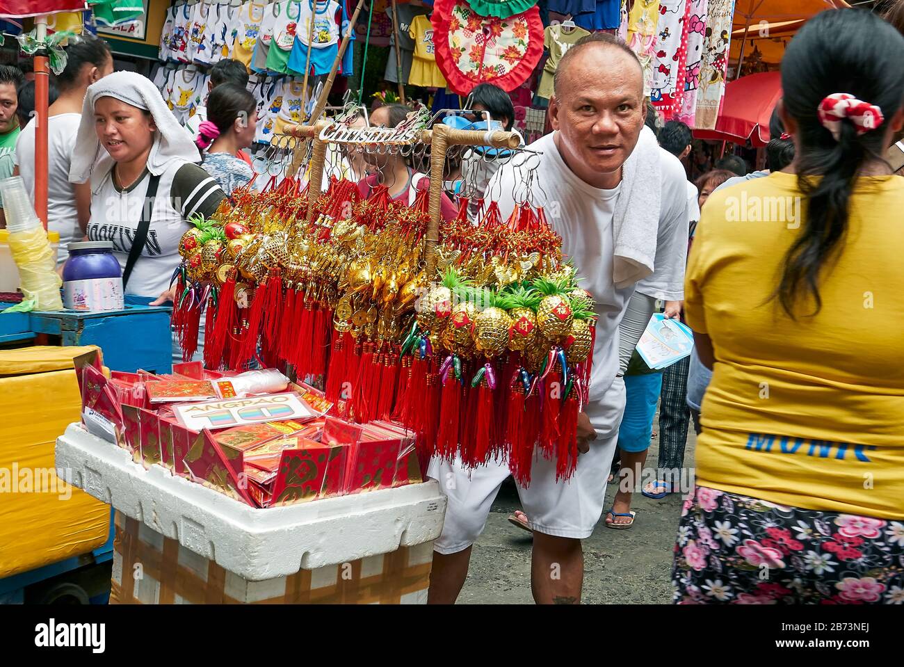 Divisoria Market, Manila, Philippinen: Freundlicher männlicher Anbieter, der Angao-Umschläge und Ananas Glücksbringer auf Lunar New Year verkauft Stockfoto