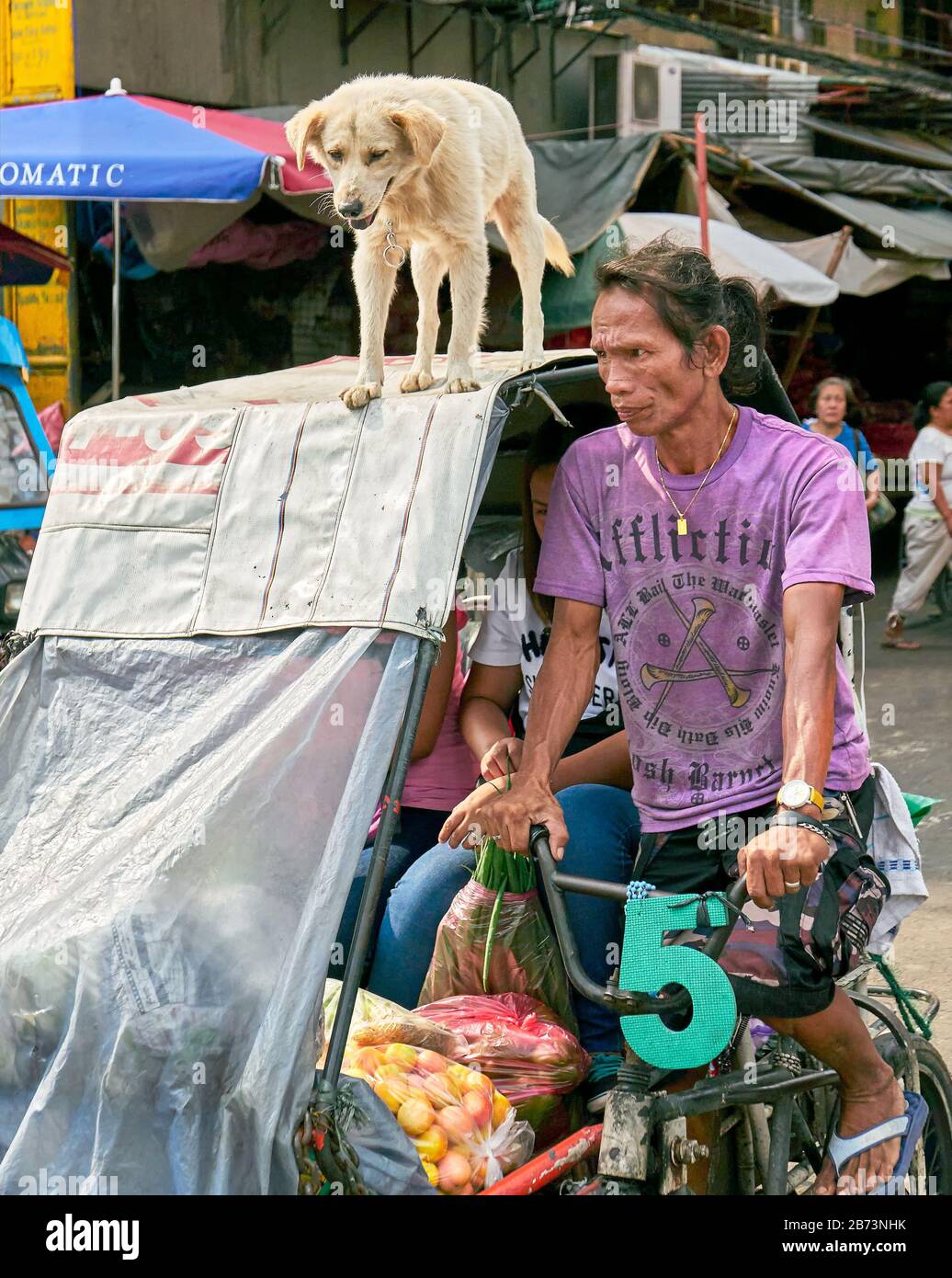 Divisoria Market, Manila, Philippinen: Ein Mann, der auf einem Pedicab reitet, Menschen mit Fracht transportiert, sein Haustierhund steht auf dem Dach Stockfoto