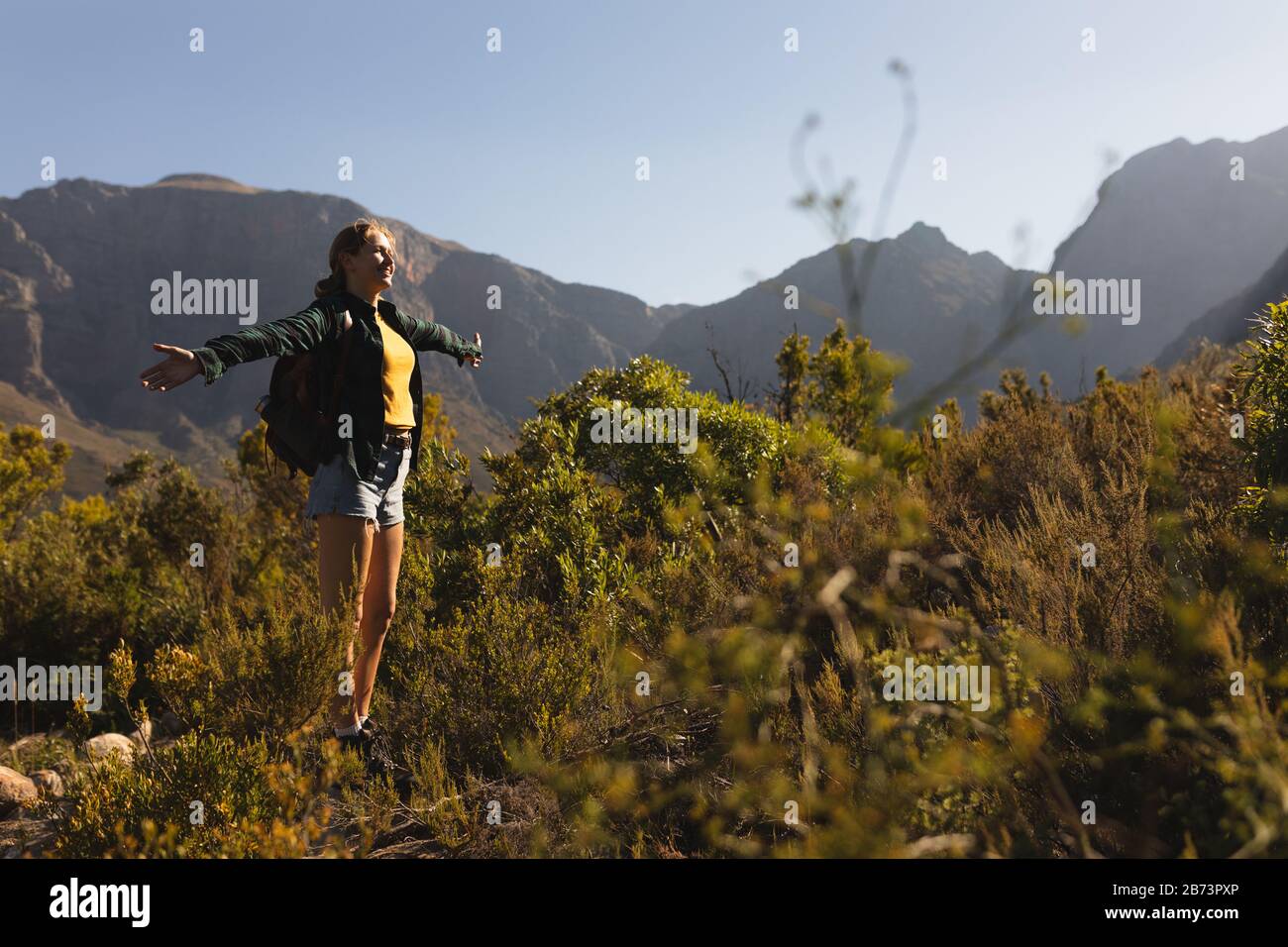 Seitenansicht der Frau mit Rucksack, der ihre Arme in die Luft hebt Stockfoto
