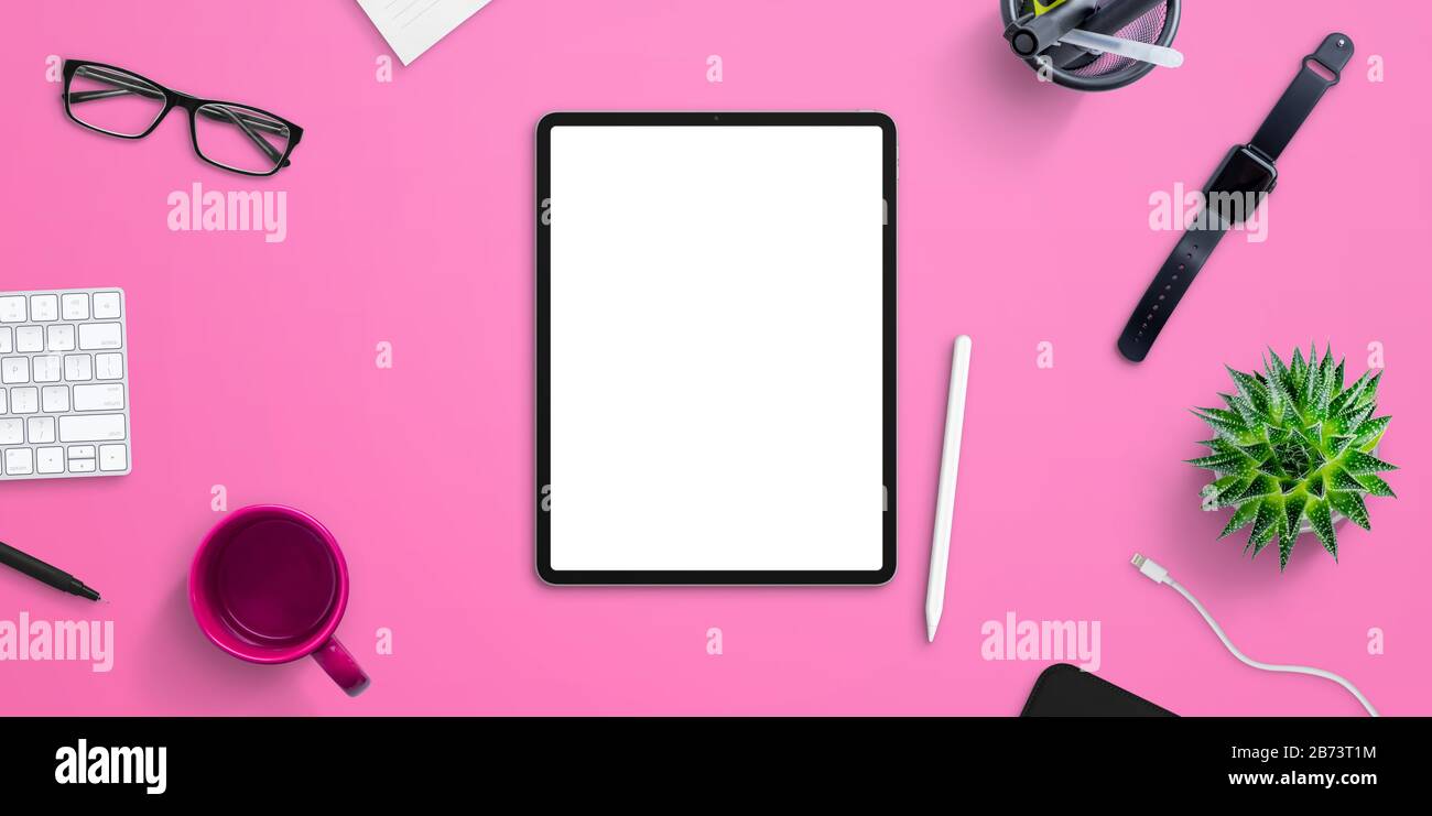 Tablet-Mockup auf pinkfarbenem Büro, Schreibtisch, umgeben von Kaffeebecher, Plant, Smart Watch, Brille, Tastatur. Draufsicht, flache Laienzusammensetzung Stockfoto