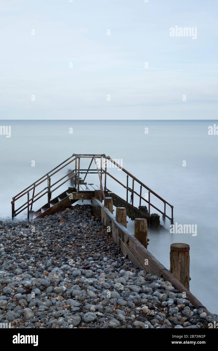 Metallstufen, die über einer Groyne an einem Strand errichtet wurden Stockfoto