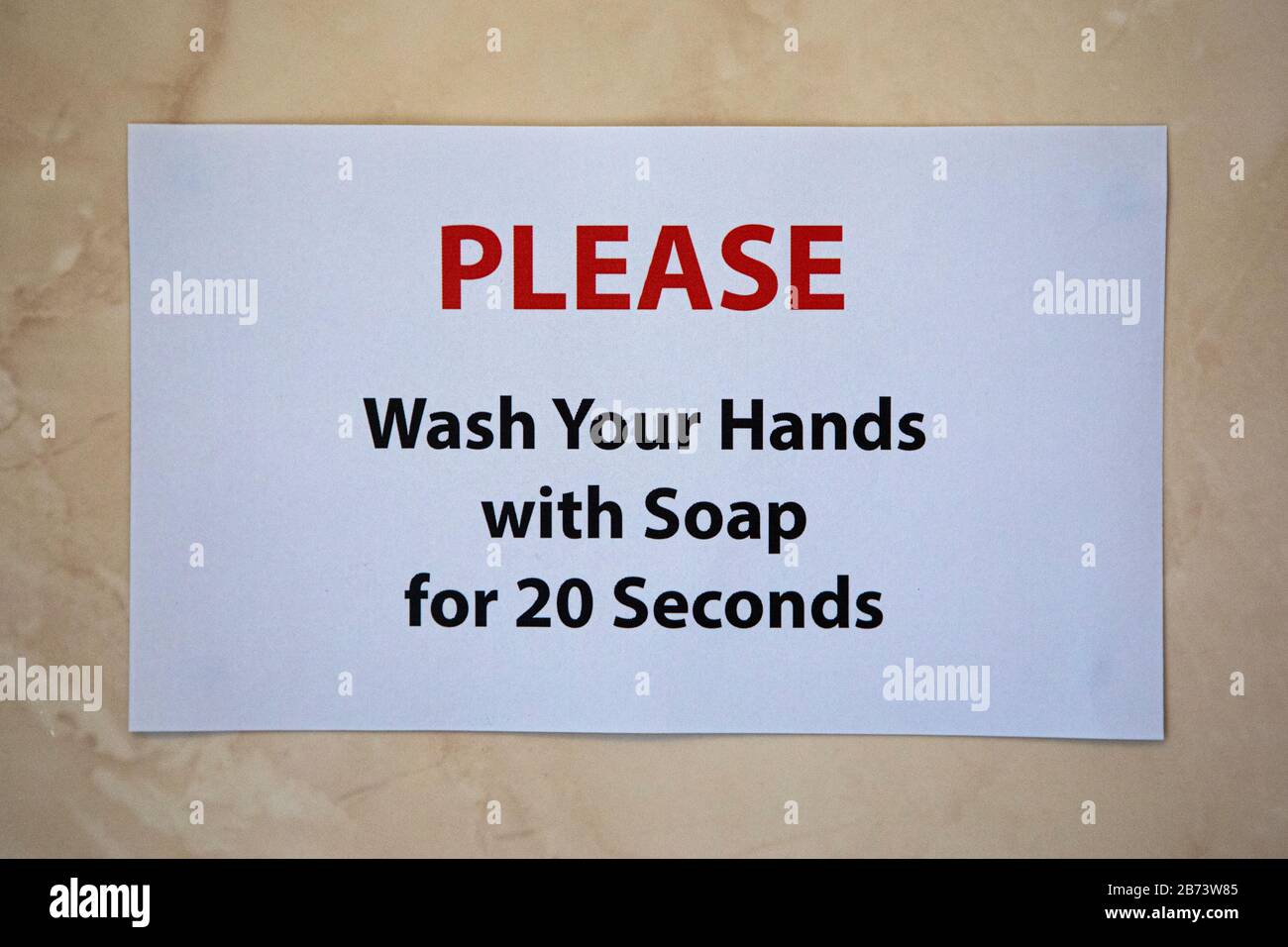 Ein Schild an der Wand des Badezimmers mit der Aufschrift "BITTE waschen Sie Ihre Hände 20 Sekunden lang mit Seife." Die empfohlene Zeit, um sich vor Viren zu schützen. Stockfoto