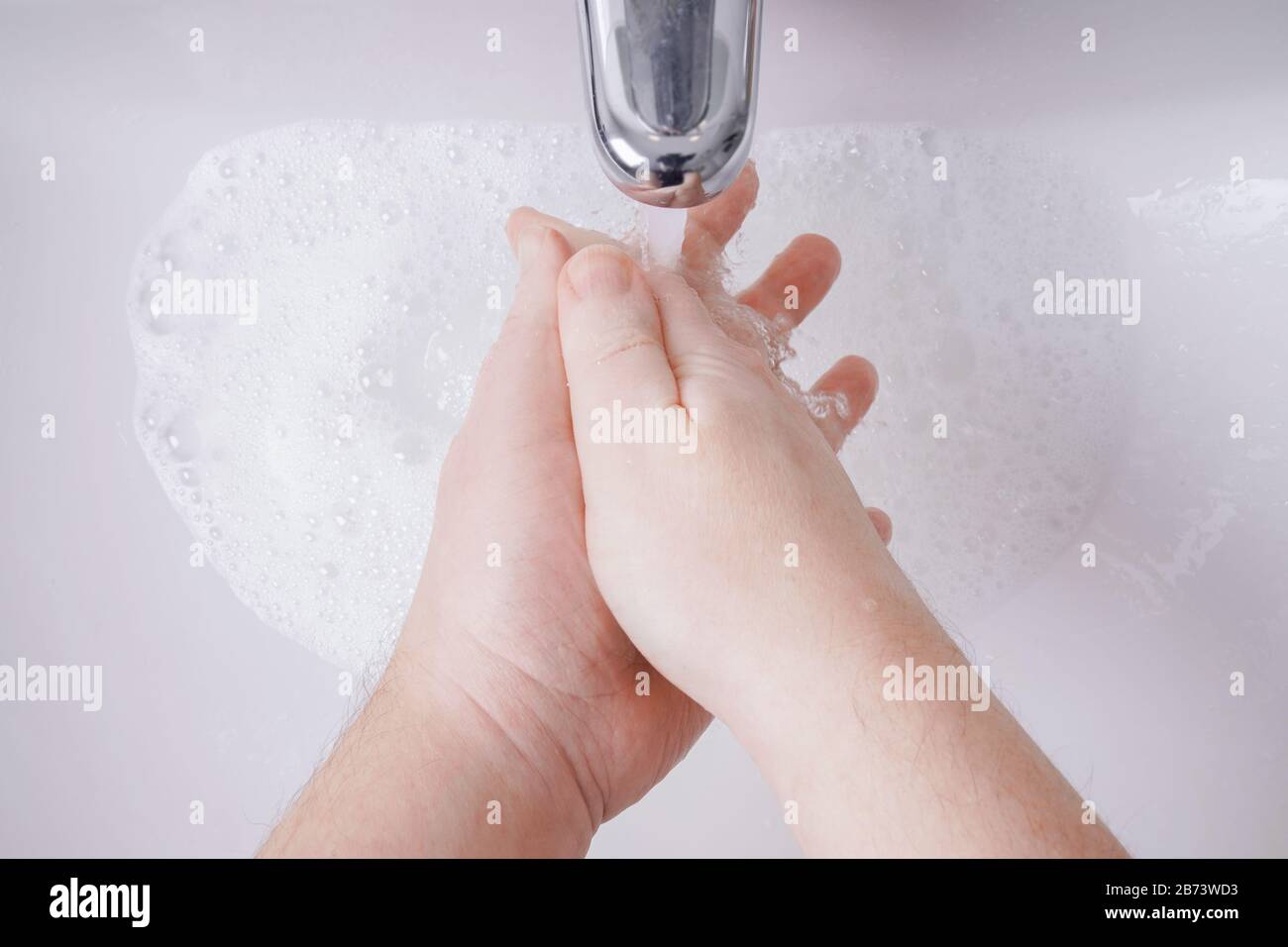 Händewaschen mit Seife und Wasser aus persönlicher Sicht - Hygienekonzept mit nicht erkennbarem männlichen Menschen und geringer Schärfentiefe Stockfoto