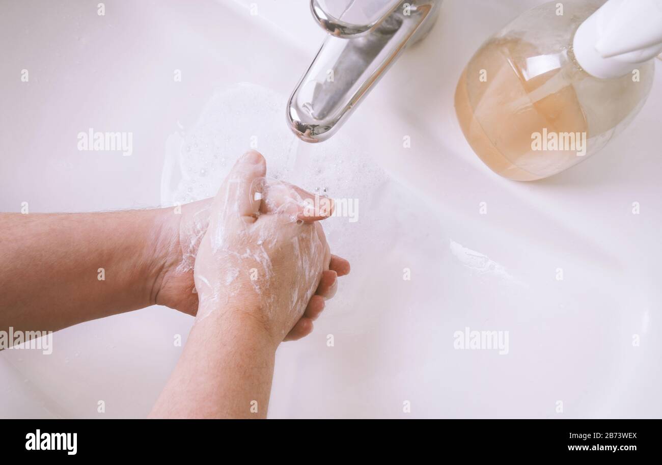 Händewaschen mit Seife und Wasser im Waschbecken oder Handbecken - Hygienekonzept mit nicht erkennbarem männlichen Menschen und geringer Feldtiefe Stockfoto