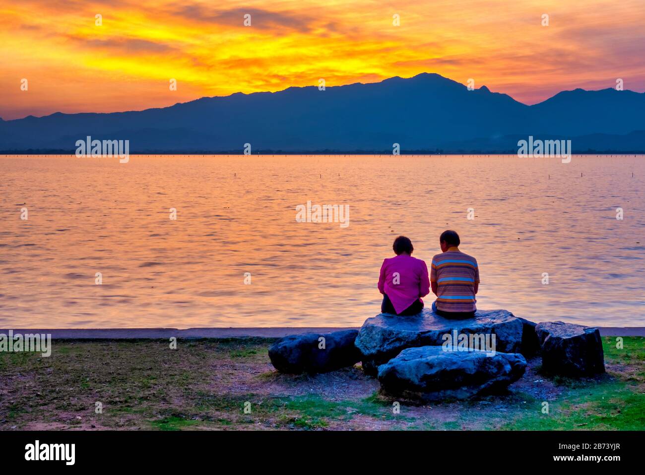 Ein Paar, das den Sonnenuntergang auf Kwan Phayao, Phayao, Thailand, beobachtet Stockfoto