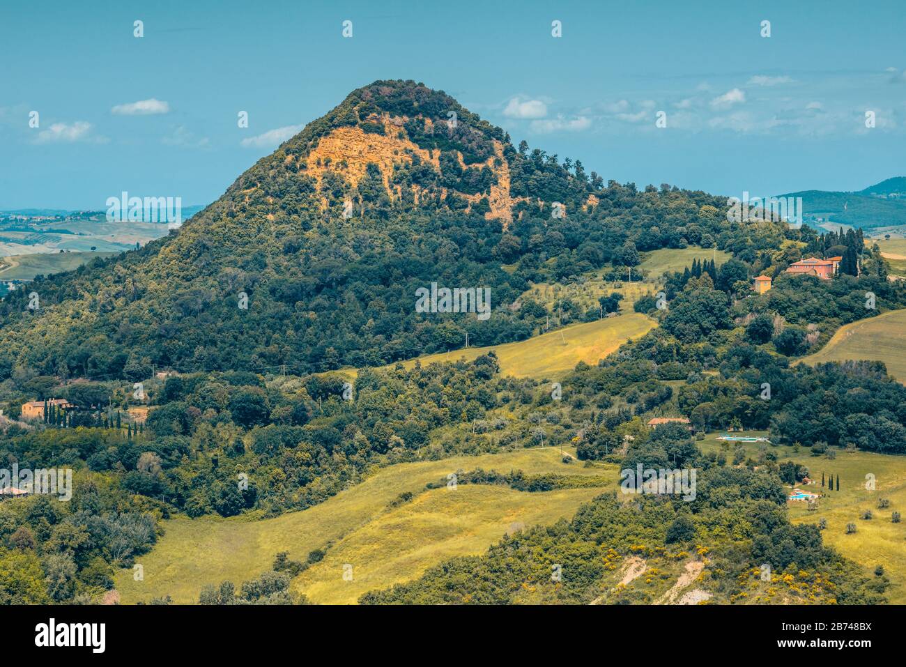 Monte Voltraio, ein Hügel mit von Wald bedeckten hängen, umgeben von Wiesen in der Nähe von Roncola außerhalb einer Bergstadt Volterra in der Toskana, Italien. Stockfoto