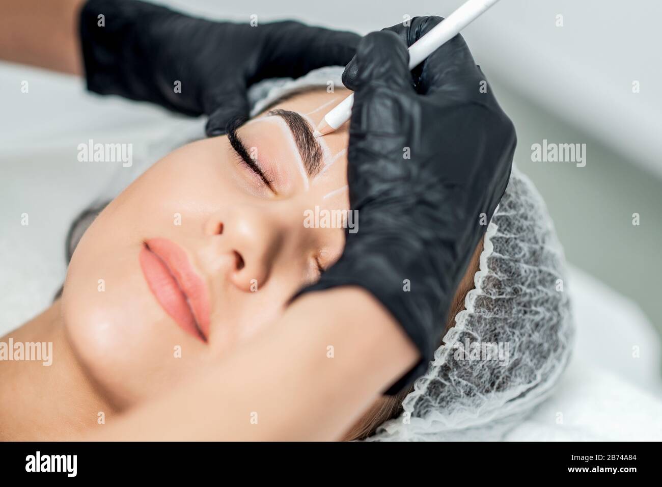 Kosmetikerin tätowieren Augenbrauen ziehen permanent Make-up. Stockfoto